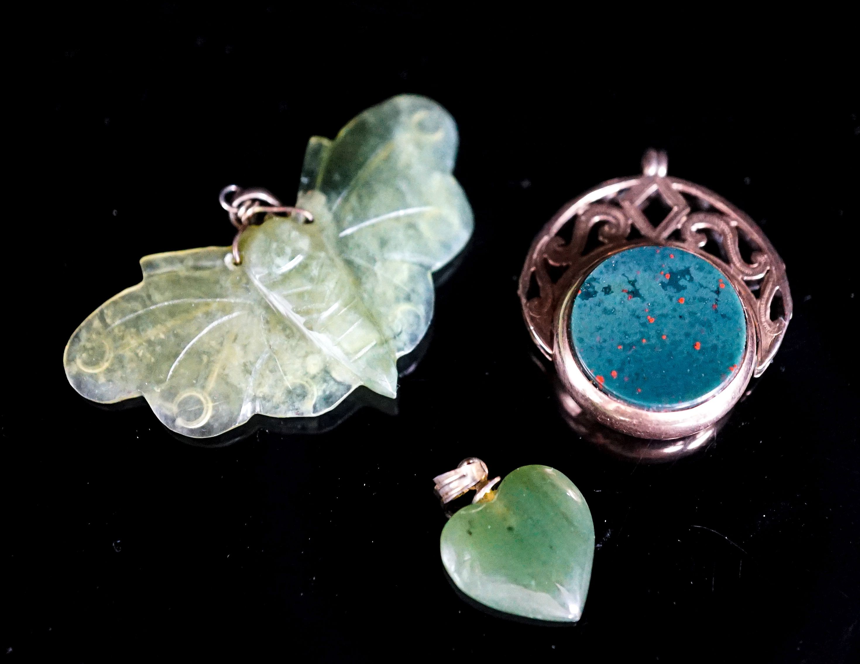 A nephrite moth pendant, 46mm, a similar heart pendant and a yellow metal mounted chalcedony spinning fob seal.